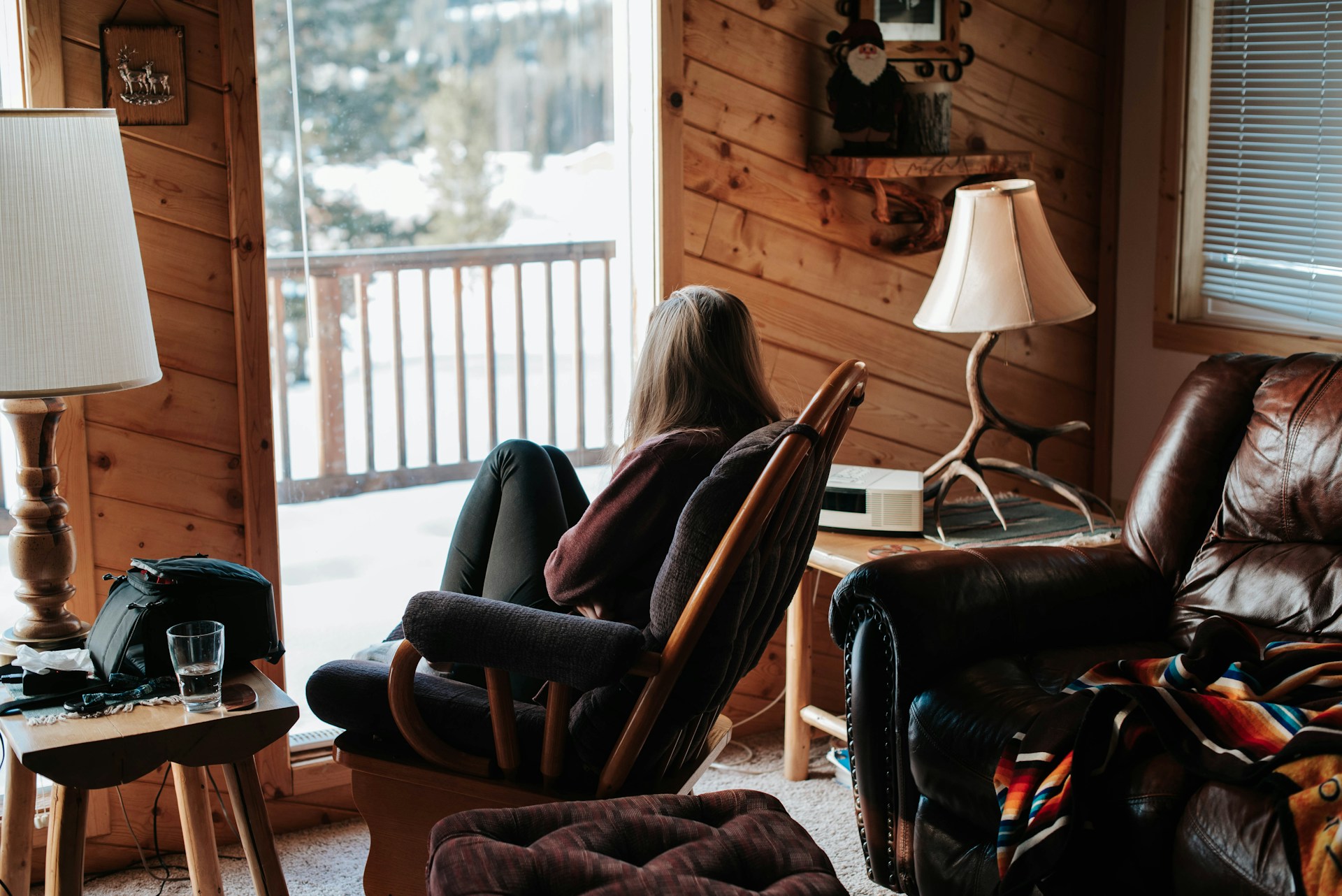 A Woman sitting on a rocking chair and looking out to the snow